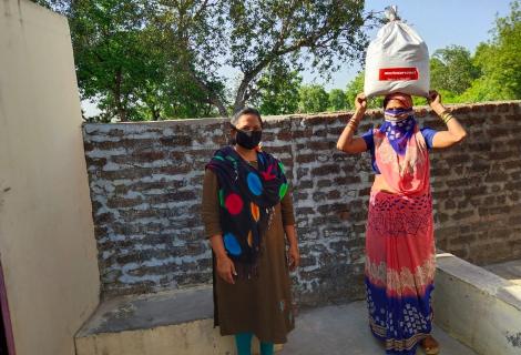 Women in India carrying a package of Covid-19 aid